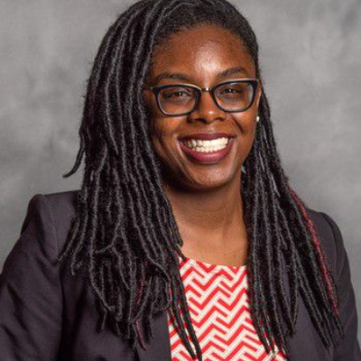 Studio portrait of Asia Dowtin facing the camera against a neutral gray background.